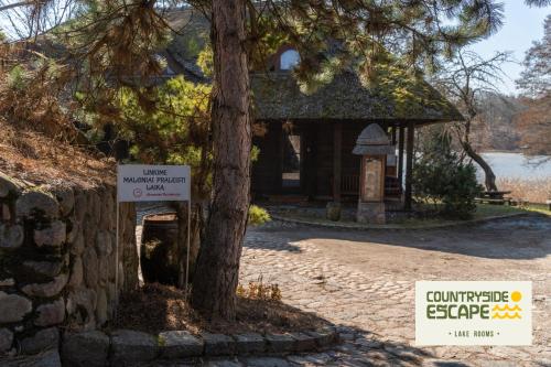 a tree with a sign in front of a building at Countryside Escape - Lake Rooms in Trakai