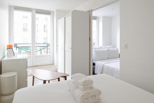 Cette chambre blanche comprend deux lits et une fenêtre. dans l'établissement Charming Apartment 1 BED 4PPL Near the Center, à Paris