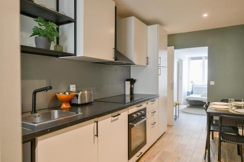 une cuisine avec des armoires blanches et un évier dans l'établissement Charming Apartment 1 BED 4PPL Near the Center, à Paris
