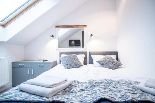 a white bedroom with a bed with a blue rug at Azymut 48C in Stary Folwark