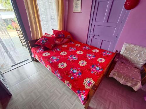 a red bed in a room with a door at Hala Rympei Homestay in Nongjrong