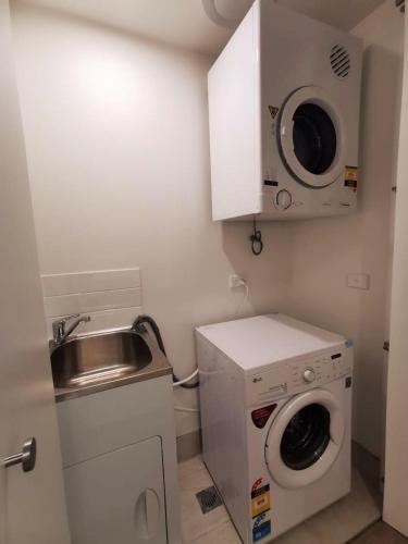 a small kitchen with a washing machine and a sink at Archer Apartment 2br with free car space in Kingston