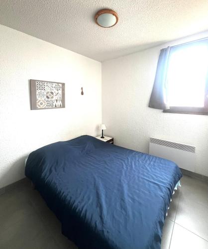 une chambre avec un lit bleu et une fenêtre dans l'établissement Lo Nidou Gruissan, à Gruissan