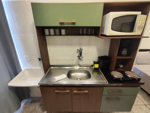 a small kitchen with a sink and a microwave at Villa Bilac - Amplos Studios 2km da Vila Germânica in Blumenau