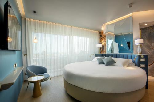 a hotel room with a large bed and a chair at Ambasciatori Suite Hotel in Sottomarina