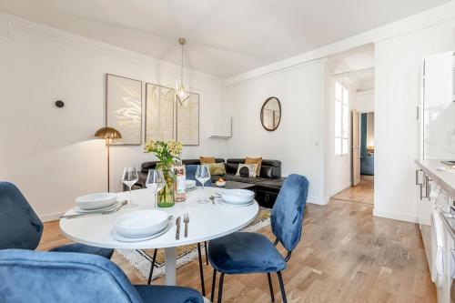 une salle à manger blanche avec une table blanche et des chaises bleues dans l'établissement A32#Republique # Marais # 1BedRoom # Paris03 # AC, à Paris