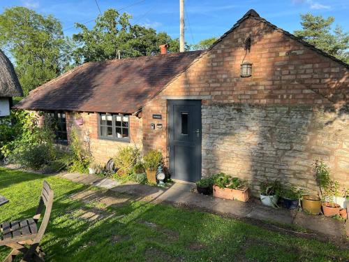 an old brick house with a black door at The Bakehouse in Castlemorton