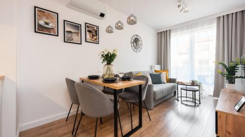 Una sala de estar con una mesa y sillas y un sofá. en Flatbook Apartamenty - Trimare Sztutowo z bilardem i parkingiem, en Sztutowo
