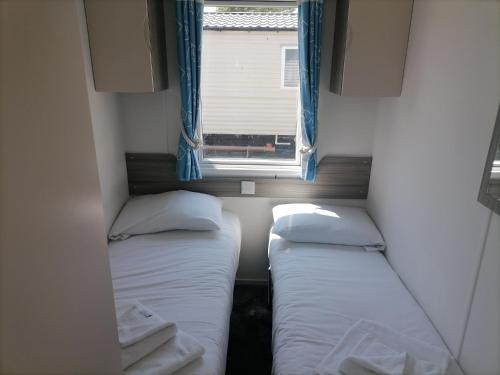 two beds in a small room with a window at Seaside retreat - 3 bedrooms with decking sleeps 8 in Kent