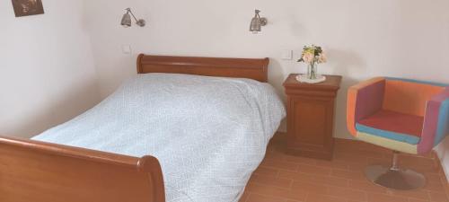 une chambre avec un lit et une chaise dans l'établissement Charme authentique au coeur de saint victor malcap, à Saint-Victor-de-Malcap