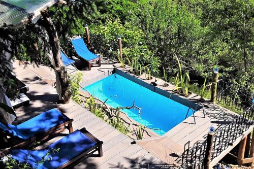 - une piscine avec 2 chaises bleues sur une terrasse dans l'établissement Le Vertige du Tigre, à Courniou