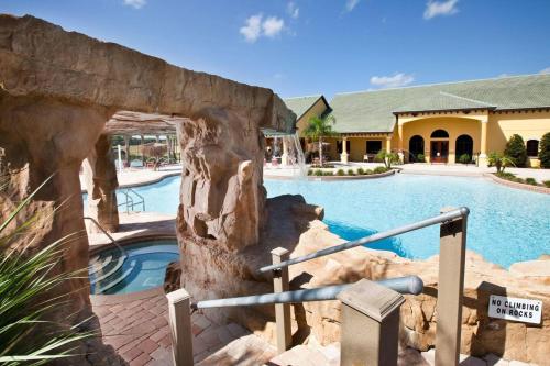 a pool at a resort with a rock wall at 9008 Paradise Palms Blissful Haven 5-Bed Oasis of Luxury and Tranquility in Orlando