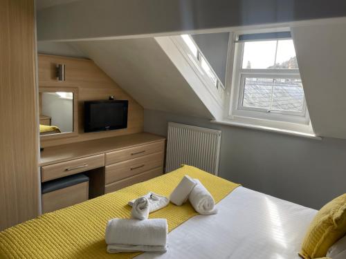 a bedroom with a bed with towels and a tv at The Wildings Hotel & Tudno's Restaurant in Llandudno
