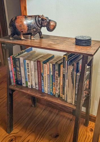 un estante de libros lleno de libros con un elefante de juguete en la parte superior en Peaceful cabin with pool on tropical south coast, en Port Edward