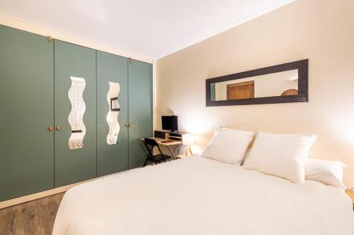 - une chambre avec un lit blanc et des armoires vertes dans l'établissement GuestReady - Modern Comfort in the Heart of Paris, à Paris