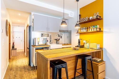 une cuisine avec un comptoir en bois et deux tabourets dans l'établissement GuestReady - Modern Comfort in the Heart of Paris, à Paris