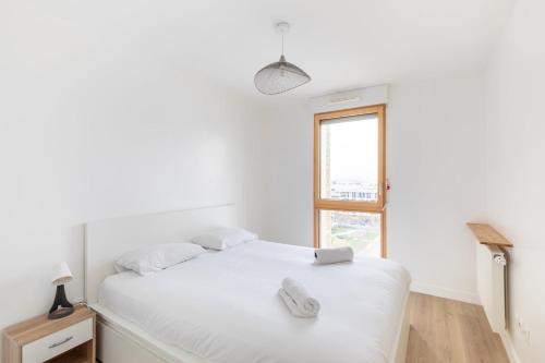 une chambre blanche avec un lit et une fenêtre dans l'établissement GuestReady - Architect-Designed Retreat near Paris, à Aubervilliers
