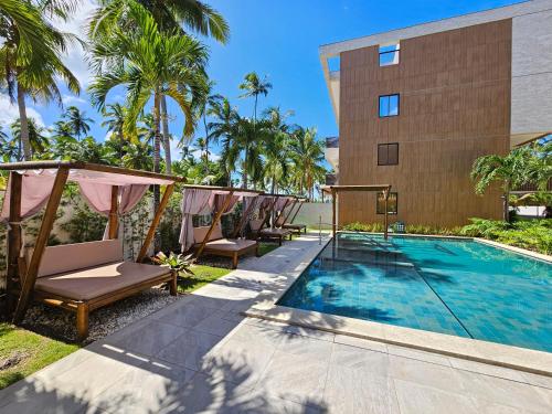 une piscine avec des chaises et un bâtiment dans l'établissement Amura Carneiros - Pé na areia - Trecho Exclusivo, à Praia dos Carneiros