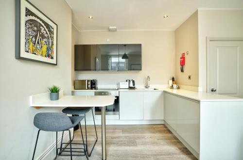 a kitchen with white cabinets and a table and chairs at Apt 4, 10 Kingsway in a stylish Georgian Building in Altrincham