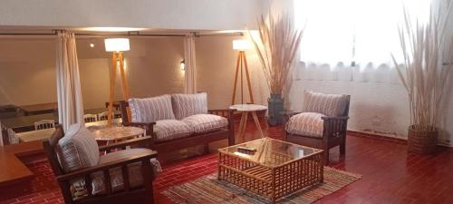 a living room with chairs and a couch and a table at Posada los Cedros in La Cumbre