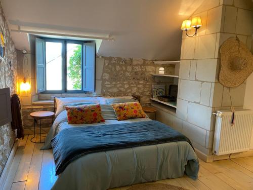 una camera da letto con un letto con lenzuola blu e una finestra di Gîte Eucalyptus L'Ecrin de Verdure piscine Chinon a Ligré