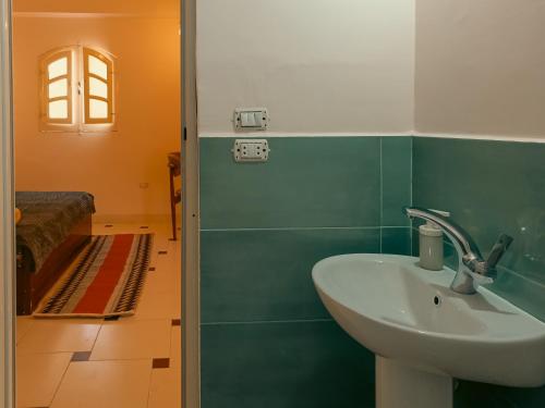 a bathroom with a sink and a room with a bed at Bonita Chillhouse in Aswan