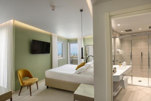 a bedroom with a bed and a bathroom with a sink at Ambasciatori Suite Hotel in Sottomarina