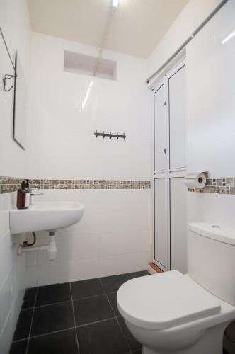a white bathroom with a toilet and a sink at Aayu Church St - 7 mins to Esplanade, George Town in George Town