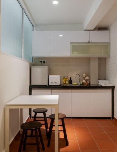 a kitchen with white cabinets and a table and stools at Aayu Church St - 7 mins to Esplanade, George Town in George Town