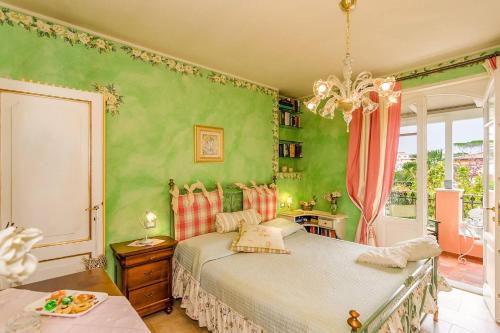 a bedroom with green walls and a bed and a chandelier at Forte dei Marmi House - with Jacuzzi in Cinquale
