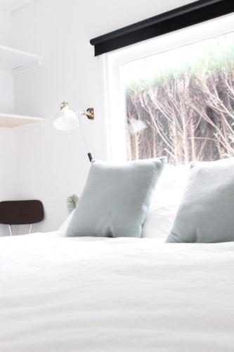 a bed with white sheets and pillows and a window at Cozy cottage with nice wood stove and veranda in Putten