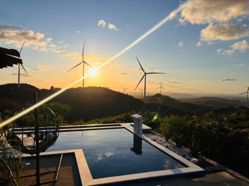 ein Pool mit Windmühlen im Hintergrund mit Sonnenuntergang in der Unterkunft Margarida 04 in Monte das Gameleiras