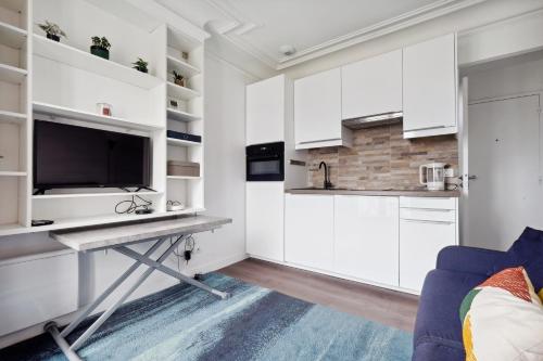 Il comprend une cuisine avec des placards blancs et un bureau avec une télévision. dans l'établissement Amazing view apartment in heart of Paris, à Paris