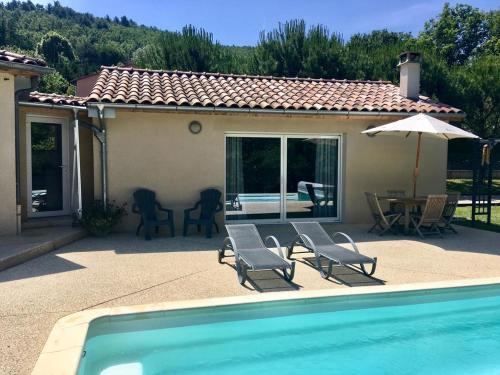 une piscine avec des chaises et une table ainsi qu'une maison dans l'établissement Le Créolia, à Saint-Vincent-de-Barrès