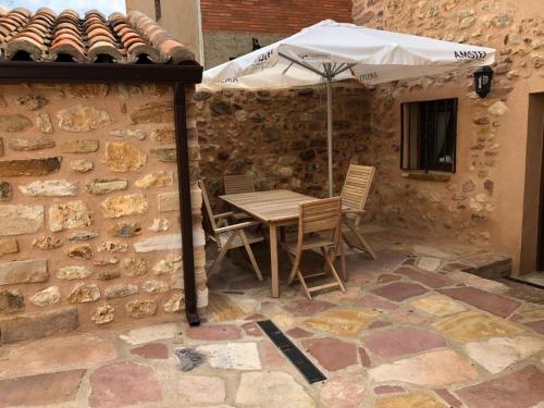 a table and chairs under an umbrella on a stone wall at La Casa El Cura in Campillo de Dueñas