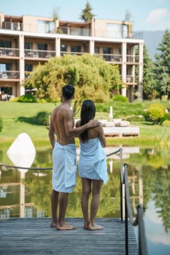 a man and woman standing on a dock near the water at Hotel Seehof Nature Retreat in Naz-Sciaves
