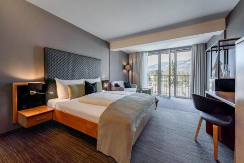 a hotel room with a large bed and a desk at Ritzenhof - Hotel und Spa am See 4-Sterne-Superior in Saalfelden am Steinernen Meer