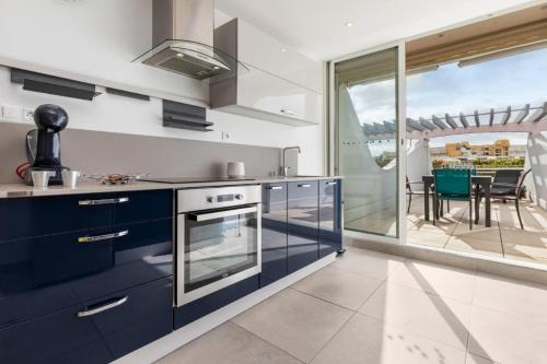 Il comprend une cuisine avec des placards bleus et offre une vue sur une terrasse. dans l'établissement Naturisme Port ambonne, au Cap d'Agde