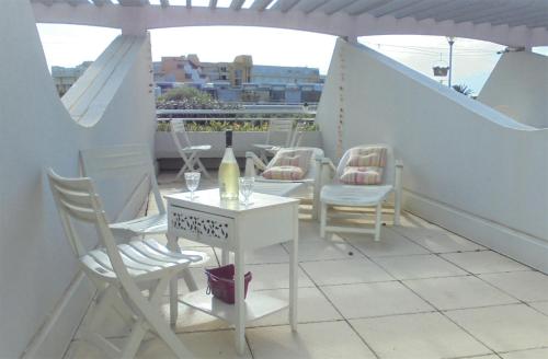 - une table et des chaises sur un balcon avec une bouteille de vin dans l'établissement Naturisme Port ambonne, au Cap d'Agde