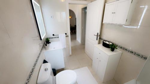 a white bathroom with a toilet and a sink at Casa Rivero in Los Alcázares
