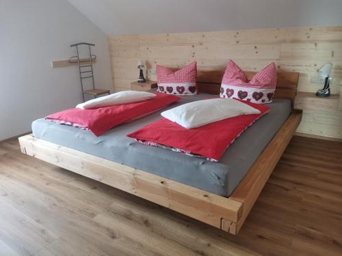 a bedroom with a large wooden bed with red and white pillows at Ferienwohnung Steible in Isny im Allgäu