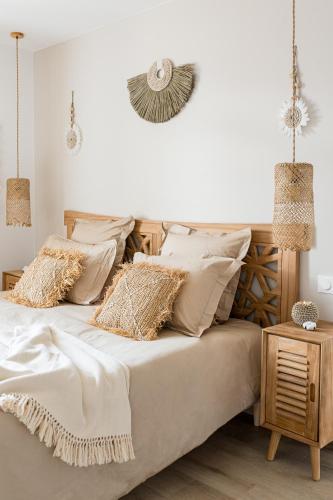 une chambre avec un lit avec des draps blancs et des oreillers dans l'établissement Suite balnéo Bali Saint-Étienne, à Saint-Étienne