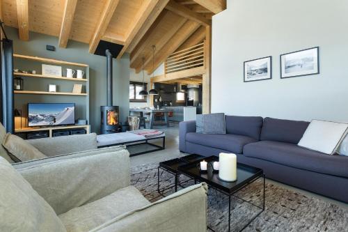 een woonkamer met 2 banken en een tv bij Chalet Aramis in La Tzoumaz