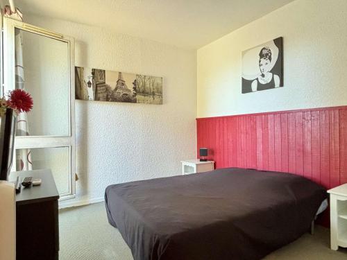 une chambre avec un lit et un mur rouge dans l'établissement Appartement 2 pièces avec garage privé et terrasse, à 80 m de la mer, classé 2 étoiles, Argelès-sur-Mer - FR-1-225-82, à Argelès-sur-Mer