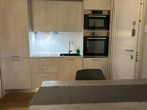 a kitchen with white cabinets and a sink and a chair at Fregene Tiny house close to the sea in Fregene