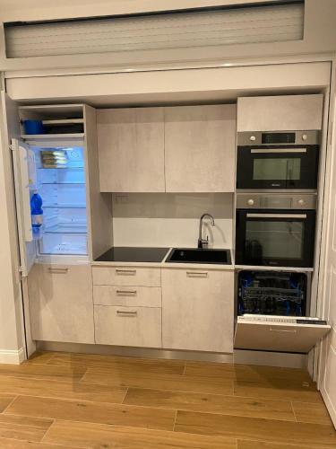 a kitchen with white cabinets and a sink and a refrigerator at Fregene Tiny house close to the sea in Fregene