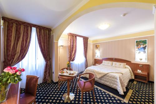 蒙特卡蒂尼泰尔梅Boutique Hotel Puccini的酒店客房带一张床、一张桌子和椅子