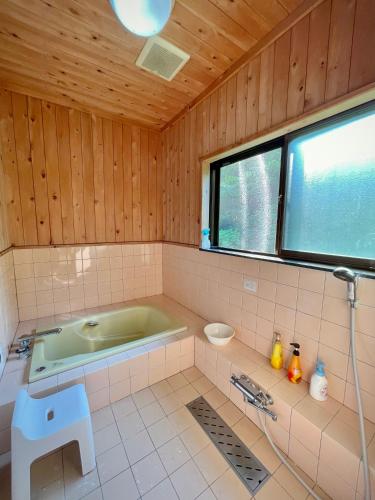 a bathroom with a green tub and a window at 白華の家 House of Hakka秋田駅秋田空港への送迎可能 in Akita