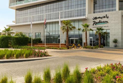 a building with palm trees in front of it at Radisson Dubai Damac Hills in Dubai