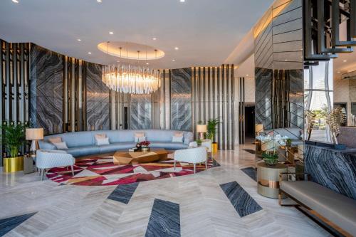a lobby with a blue couch and a table and chairs at Radisson Dubai Damac Hills in Dubai